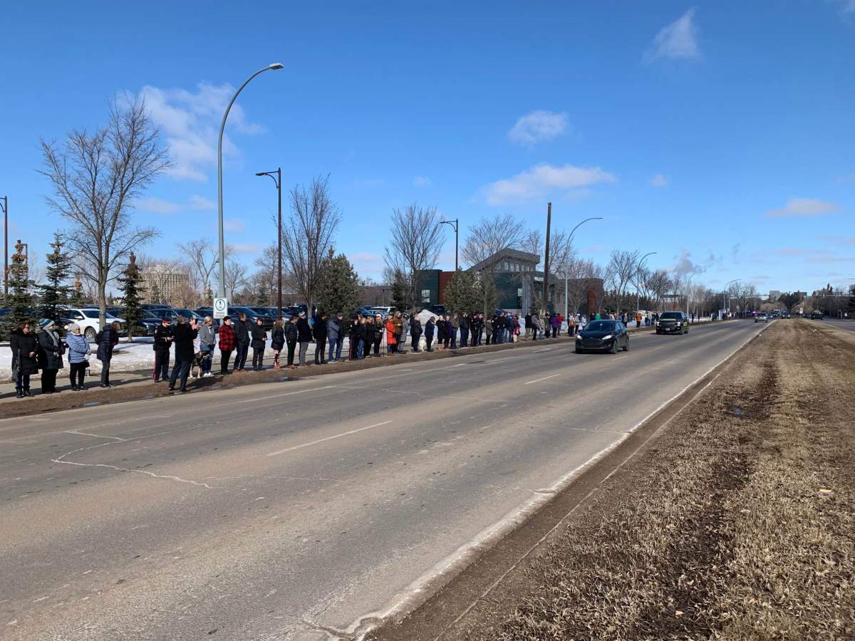 Blue ribbons are wrapped around street lights along the five-kilometre procession route taking two slain Edmonton police officers to the funeral home on Tuesday, March 21, 2023.