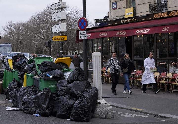 People walk past not collected garbage cans next to the Senate in Paris, Sunday, March 12, 2023. (AP Photo/Michel Euler)