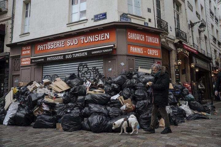 A man walks past piles of garbage in Paris, Monday, March 13, 2023. (AP Photo/Lewis Joly)