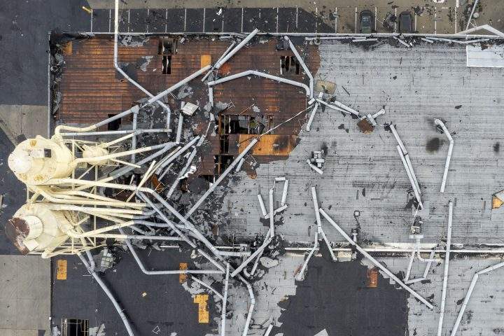 A damaged industrial building, with sections of its roof missing, is shown from above