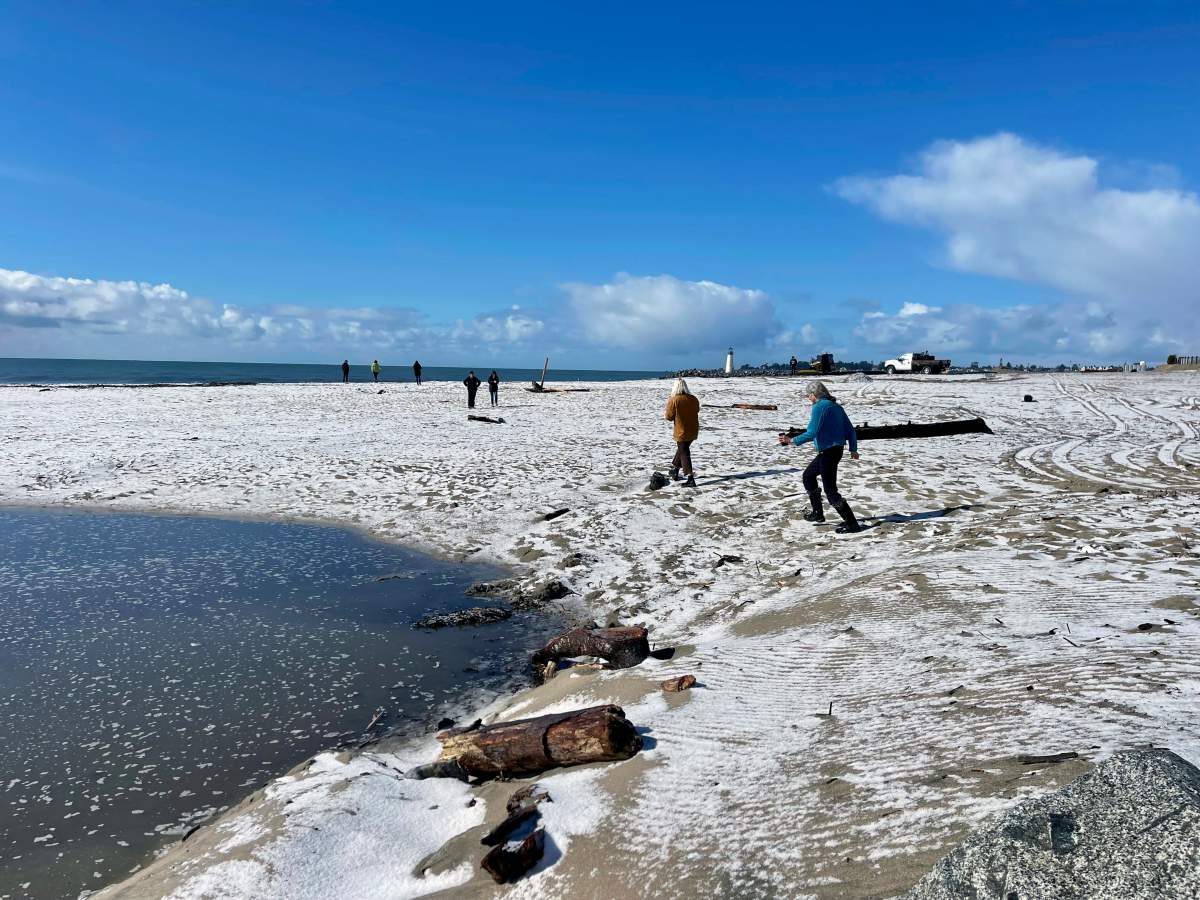 People walk along a snow-covered beach in southern California.