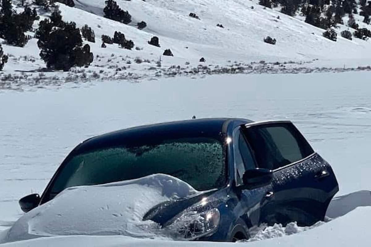 A partially buried vehicle is visible among feet of snow.
