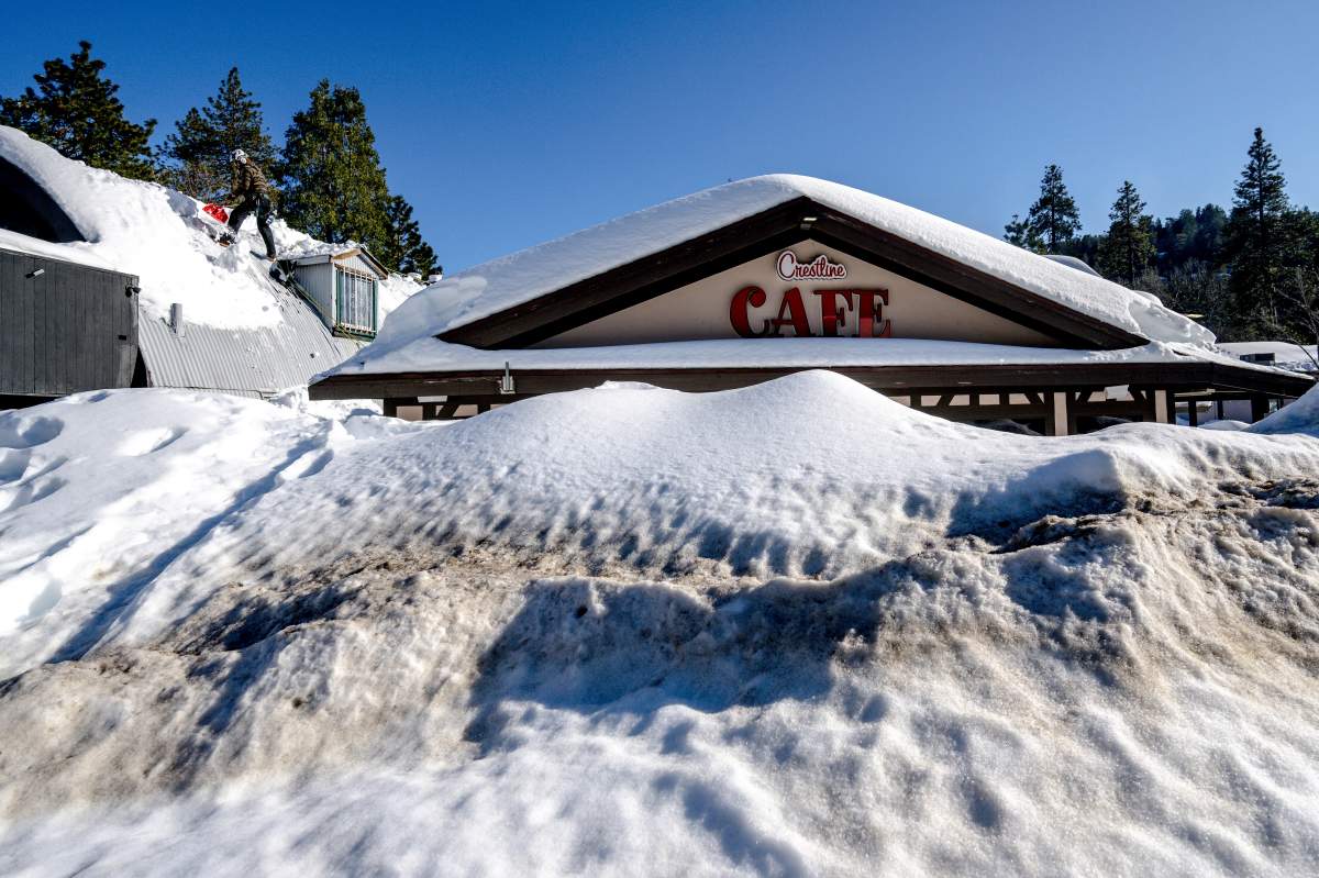 A man shovels snow off the roof of a store in southern California.