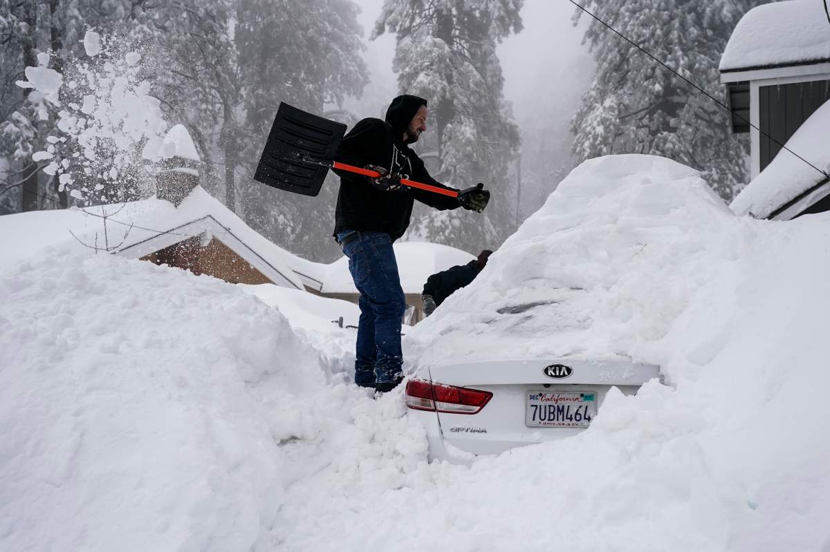 A man shovels snow off his submerged car after a snow storm hit southern California.