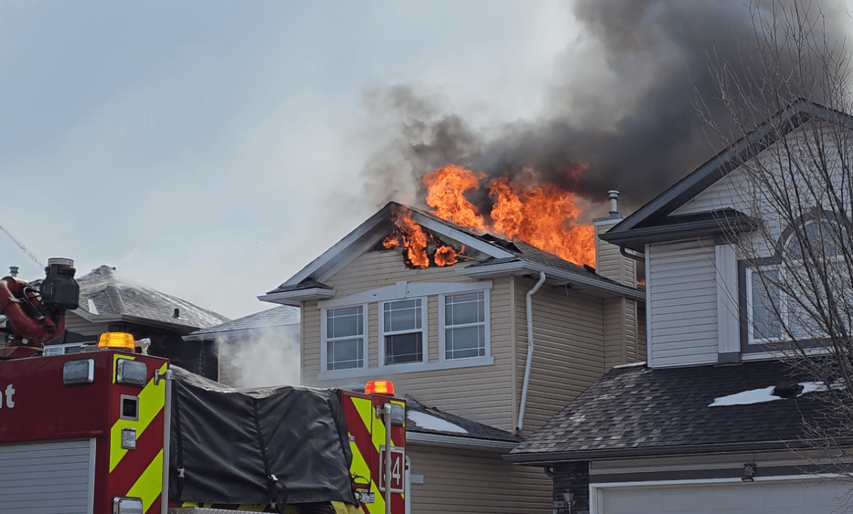 A house in Calgary's Citadel neighbourhood is seen on fire with crews attending, on March 24, 2023.