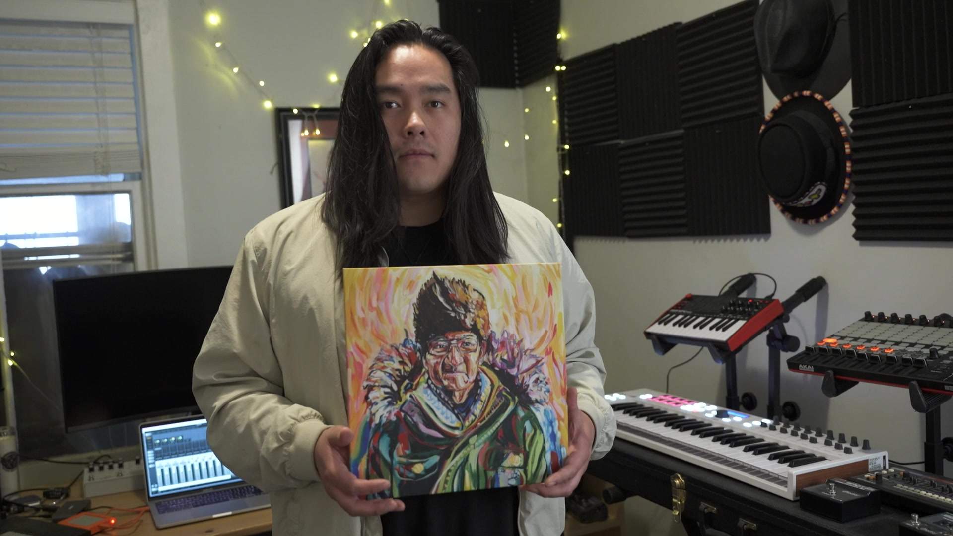 Aysanabee holds a painting by Toronto artist Montina Hussey, of his grandfather Watin, which also graces the cover of his debut album.