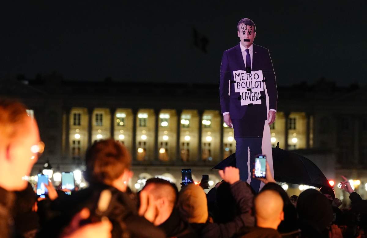 Demonstrators hold a placard depicting French President Emmanuel Macron