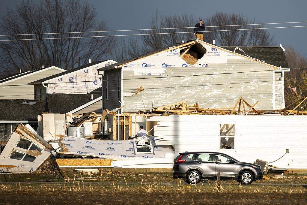 A person walks on the roof of a building damaged in a storm after a tornado warning in Johnson County, Friday, March 31, 2023, in Hills, Iowa.
