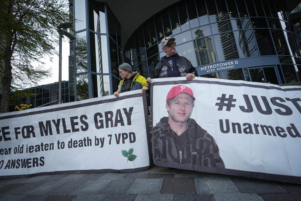 Protesters hold banners with a photograph of Myles Gray, who died following a confrontation with several police officers in 2015, before the start of a coroner's inquest into his death, in Burnaby, B.C., on Monday, April 17, 2023. The coroner presiding over the inquest says he won't allow the jury to see a photograph showing injuries at the time the 33-year-old died, because the application was made too late in the process. THE CANADIAN PRESS/Darryl Dyck.