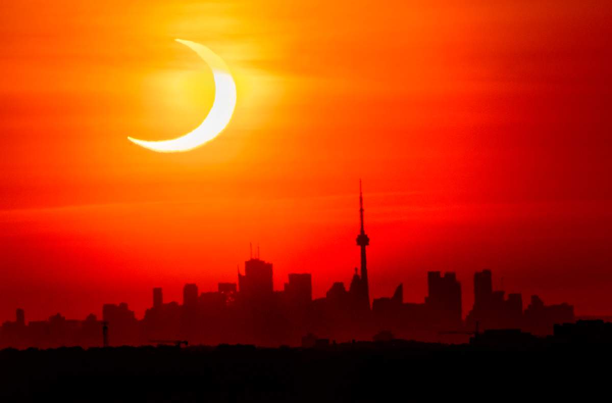 An annular solar eclipse rises over the skyline of Toronto on Thursday, June 10, 2021.