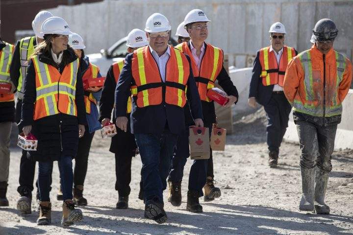 Ontario Premier Doug Ford carries coffee as Transport Minister Caroline Mulroney and Finance Minister Peter Bethlenfalvy carry donuts for workers as they visit the starting site of the Metrolinx subway extension project in Scarborough, Ontario on Friday, April 29, 2022.