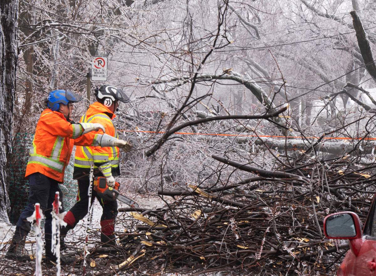 City workers clears fallen branches after Wednesday’s ice storm, which left over a million customers without power in Quebec on Thursday.