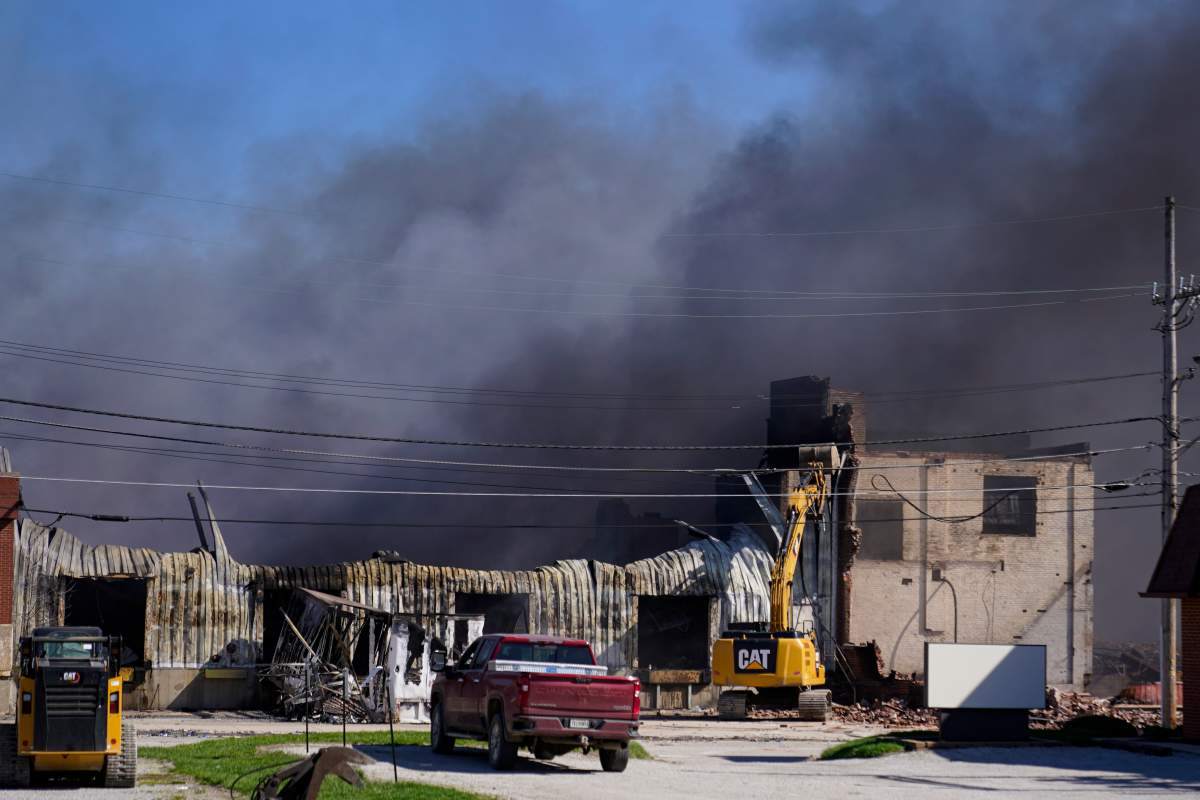 Workers knock down a section of a building at the site of an industrial fire as smoke billows in Richmond, Ind., Wednesday, April 12, 2023.