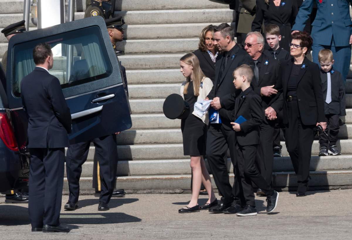 Quebec provincial police Sgt. Maureen Breau’s husband, Daniel Sanscartier, and her children, Kheraly and Emrick, leave the church after her funeral service in Trois-Rivieres, Que. on Thursday.