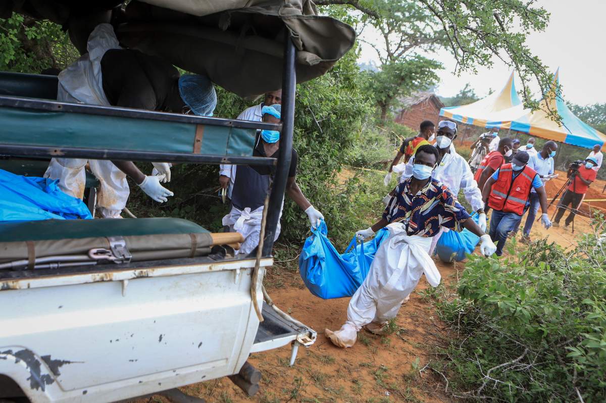 Police and local residents load the exhumed bodies of victims of a religious cult into the back of a truck in the village of Shakahola, near the coastal city of Malindi, in southeastern Kenya Sunday, April 23, 2023.