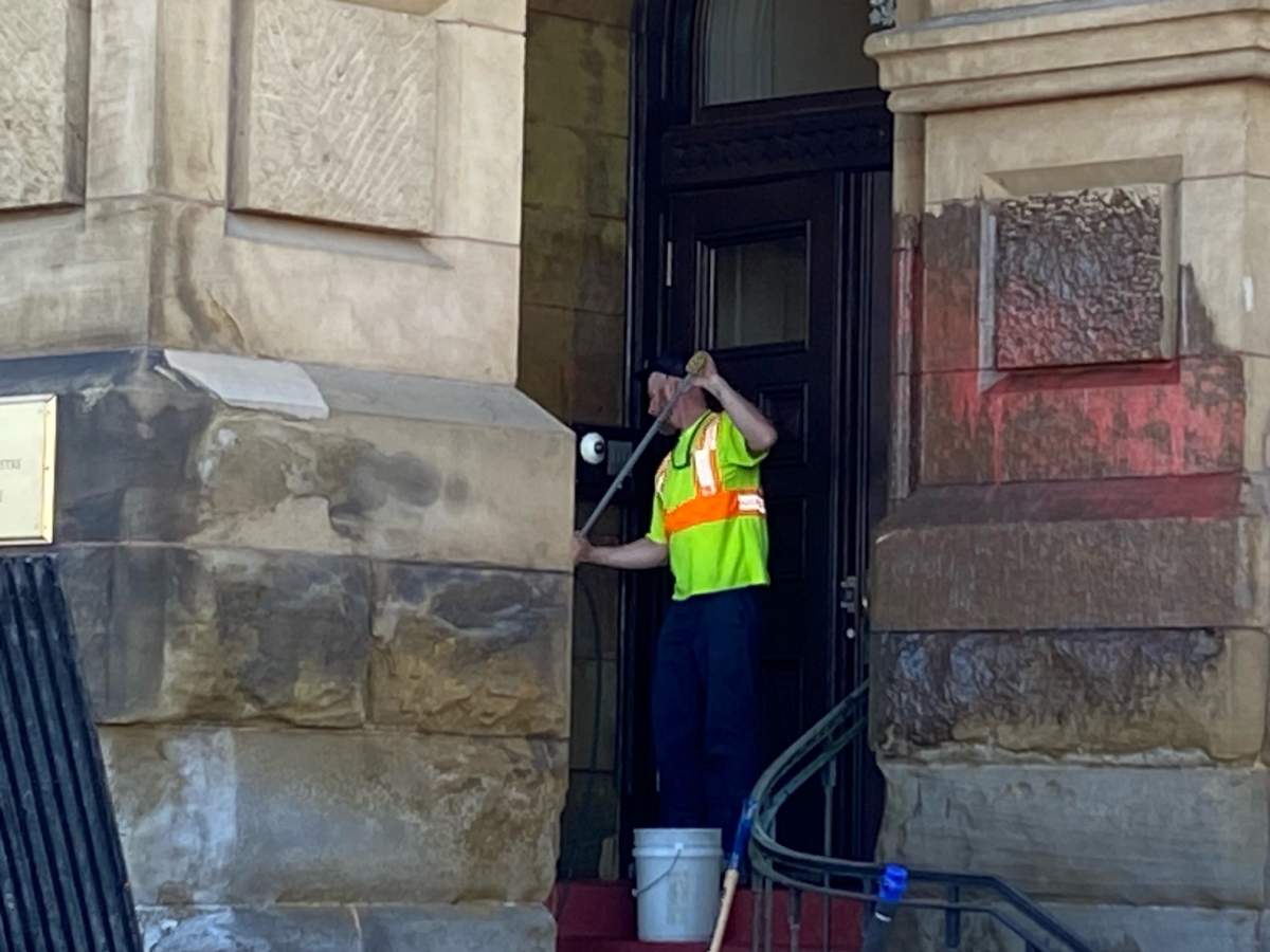 Maintenance staff remove pink paint thrown on the walls of the Prime Minister's Office by a protestor.