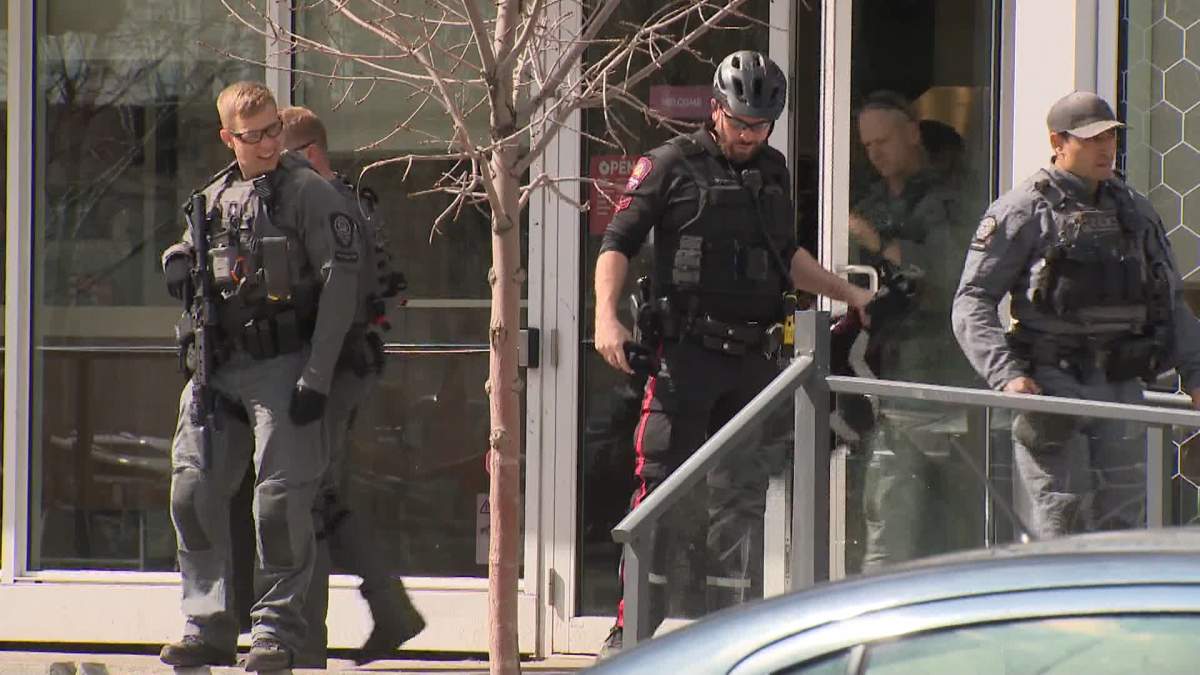Calgary police officers and tactical unit members are seen exiting a downtown coffee shop following an altercation.