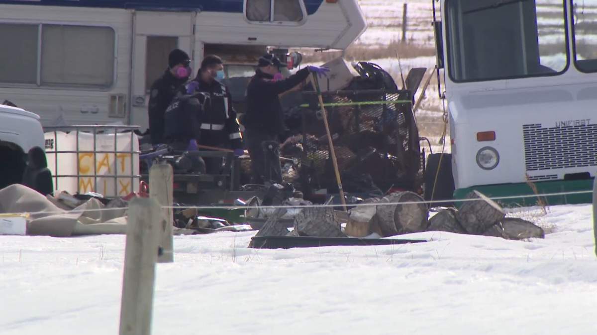 Investigators search the grounds behind a shop space near Chestermere, Alta., on April 7, 2023.