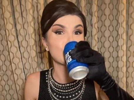 Dylan Mulvaney drinking a can of Bud Light.
