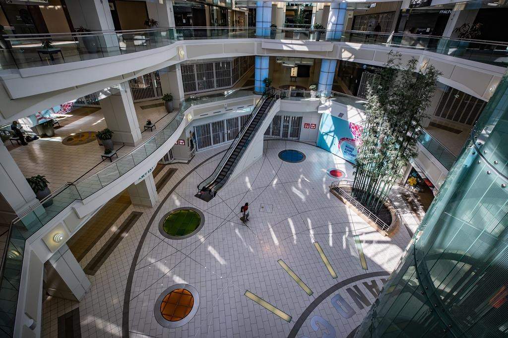 A man carries bags of groceries while walking through a deserted Metropolis at Metrotown shopping mall in Burnaby, B.C., on Sunday, April 12, 2020. THE CANADIAN PRESS/Darryl Dyck.