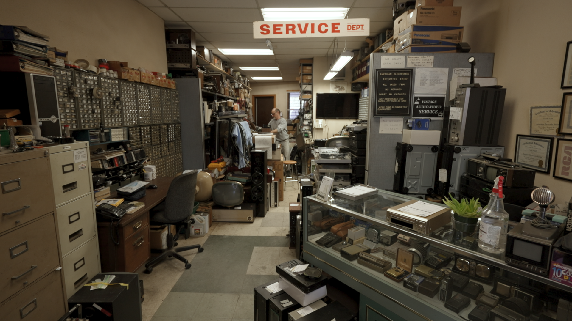 The interior of American Electronics. Devices, new and old, line the walls waiting to be diagnosed and repaired.