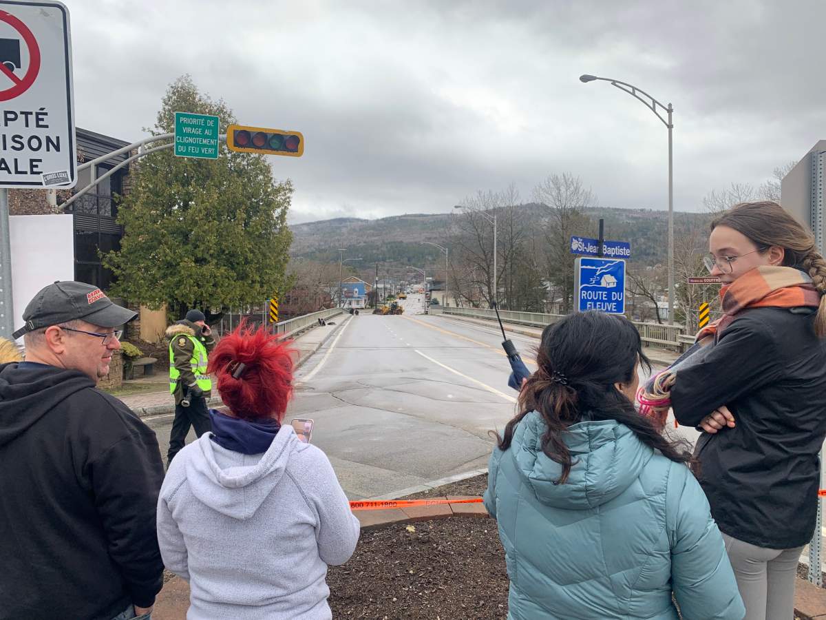 Baie-Saint-Paul residents stand near a closed street due to flooding on May 2, 2023.