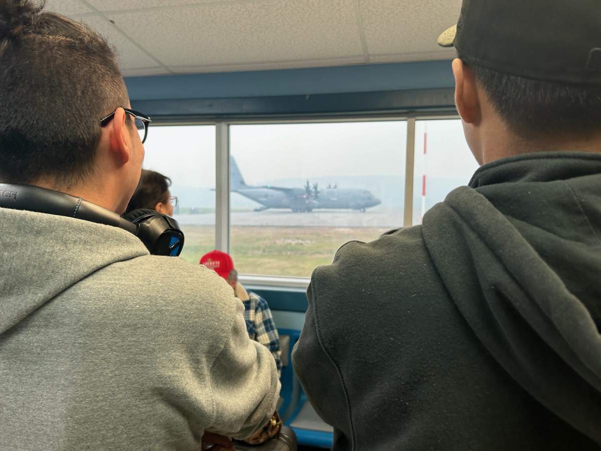 Residents looking at the Canadian Armed Forces C-130J Hercules aircraft being used to transport Alberta wildfire evacuees out of Fort Chipewyan on Tuesday, May 30, 2023.