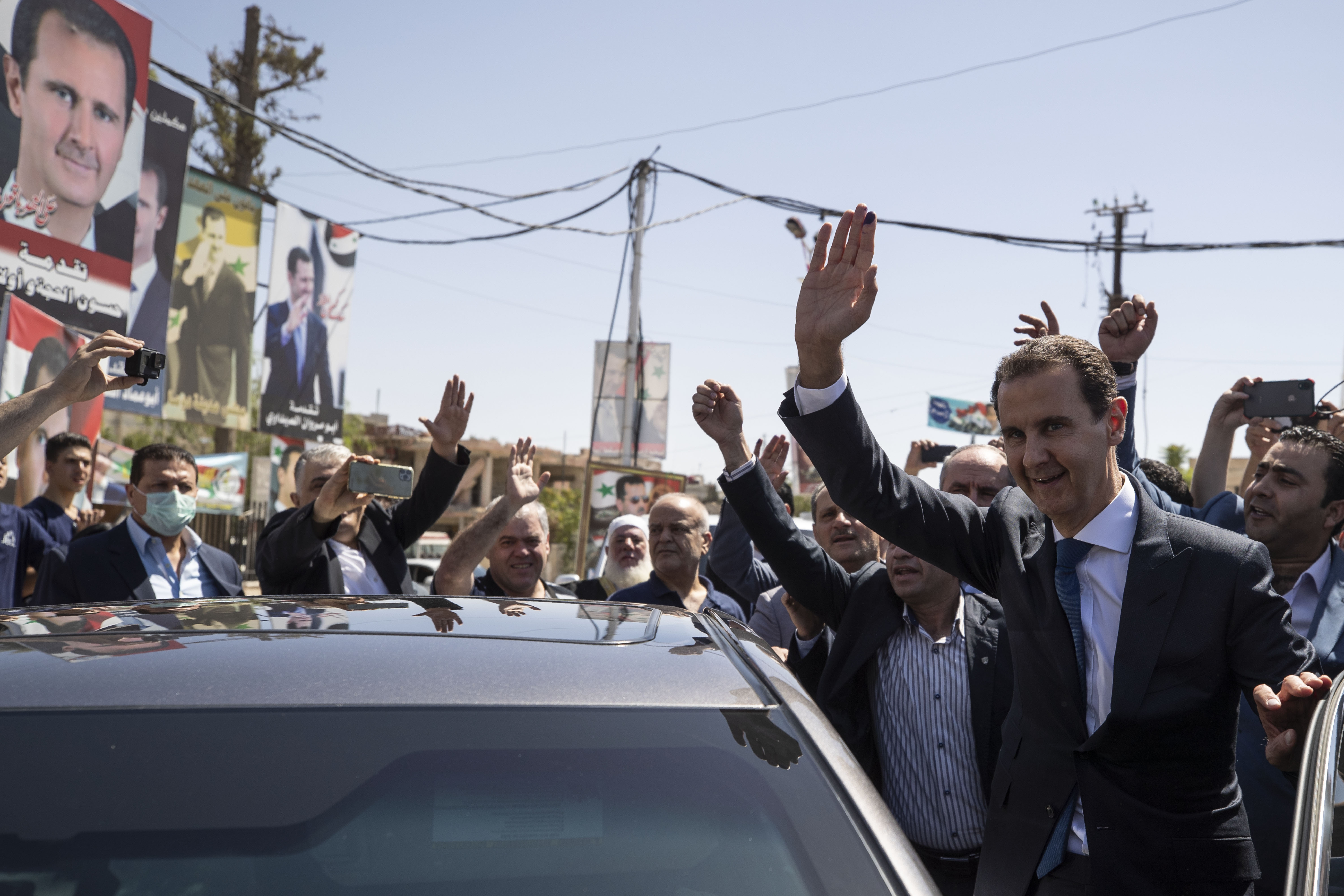 Syrian President Bashar Assad, right, waves to supporters in the town of Douma, in the eastern Ghouta region, Syria, on May 26, 2021. (AP Photo/Hassan Ammar)