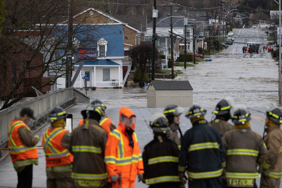 Firemen line up by the Bas-du-Nord river as the bridge is closed because of flooded roads, Monday, May 1, 2023 in Baie Saint-Paul, Quebec.
