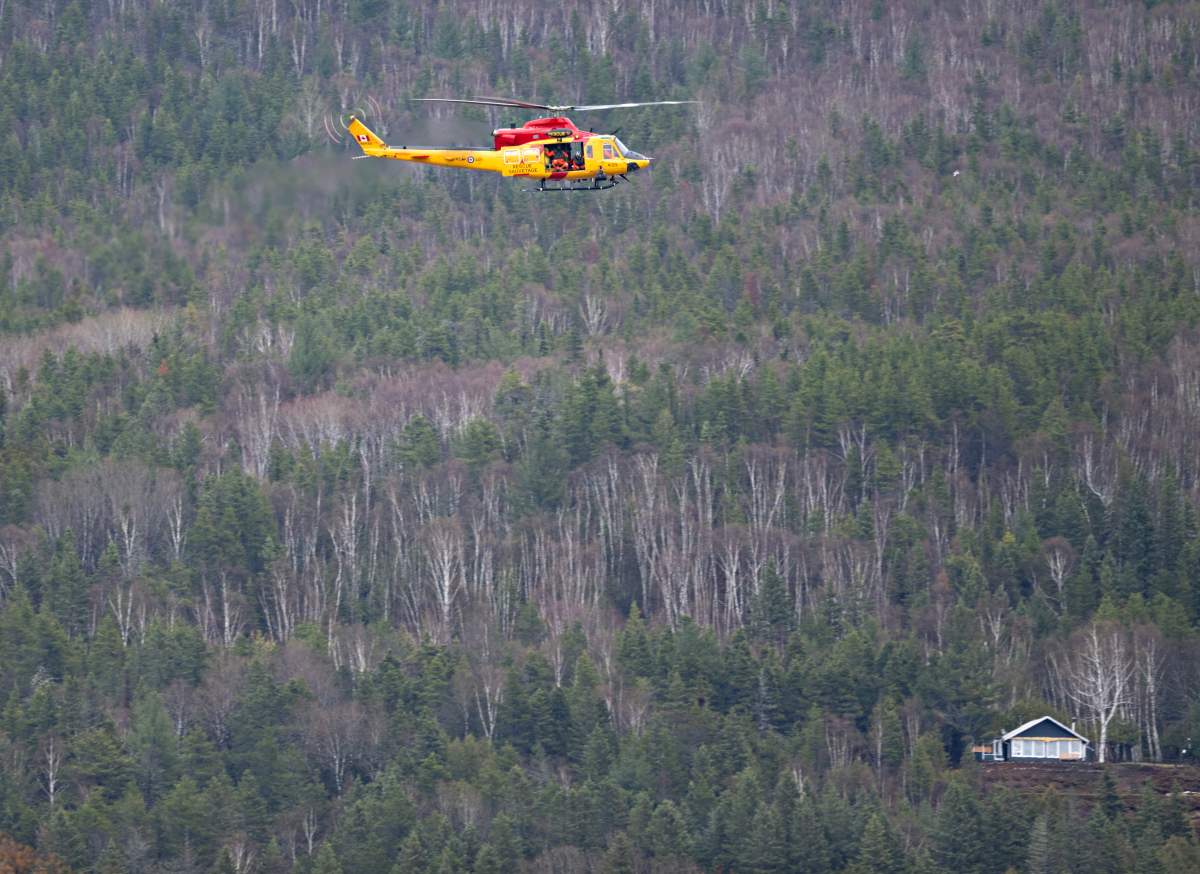 A search and rescue helicopter patrols the flooded area, looking for two missing people on Monday, May 1, 2023 in Baie-Saint-Paul, Quebec.