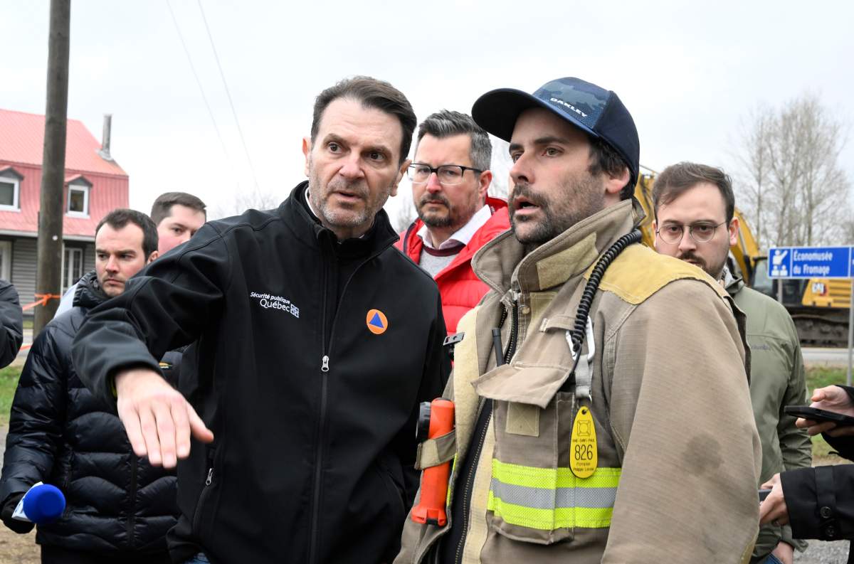 Quebec Public Security Minister Francois Bonnardel speaks with local firefighter Philippe Lavoie who early lost his house during major spring floods, Tuesday, May 2, 2023 in Baie-Saint-Paul Que.
