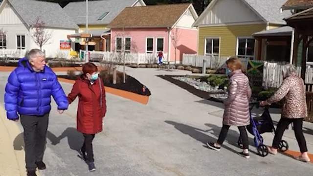 Alan (far left) with his friend Carole (middle left) pass by another resident at the Village Langley.
