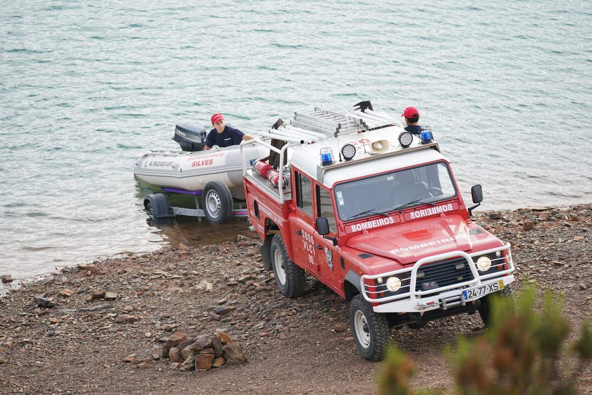 A truck unloading a dinghy into water.