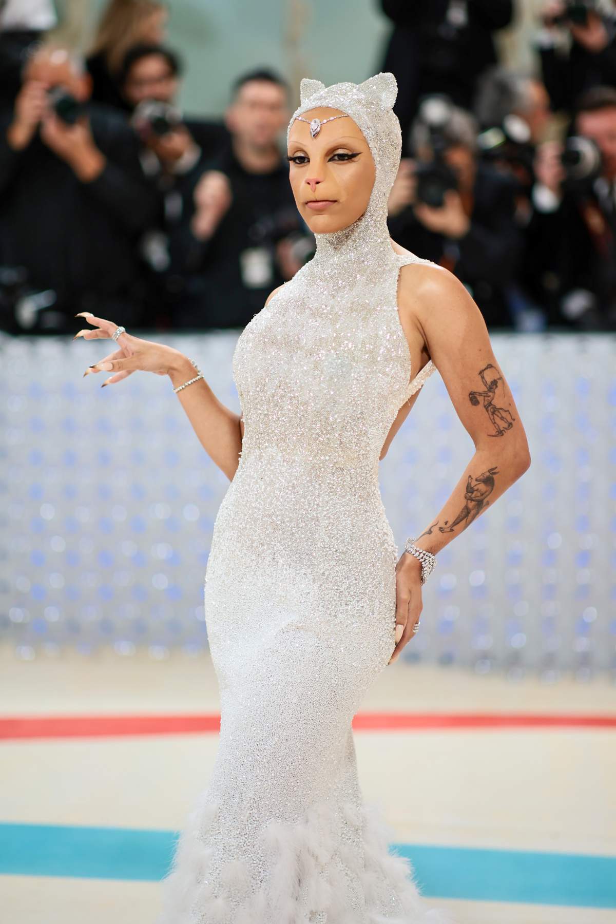 Doja Cat in a sparkly dress with a hood and cat ears. Her make up is done to look like a cat.