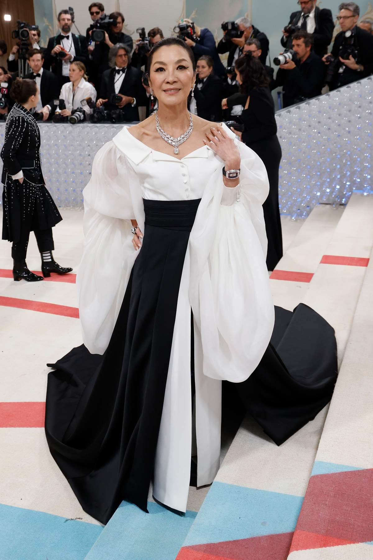 Michelle Yeoh in a flowy black and white gown. The sleeves and train of the dress are billowed.