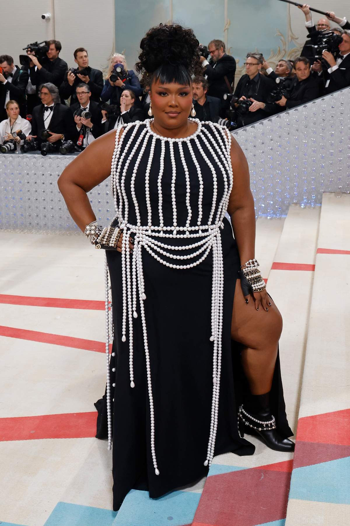 Lizzo wearing a full-length black dress adorned in strings of pearls.