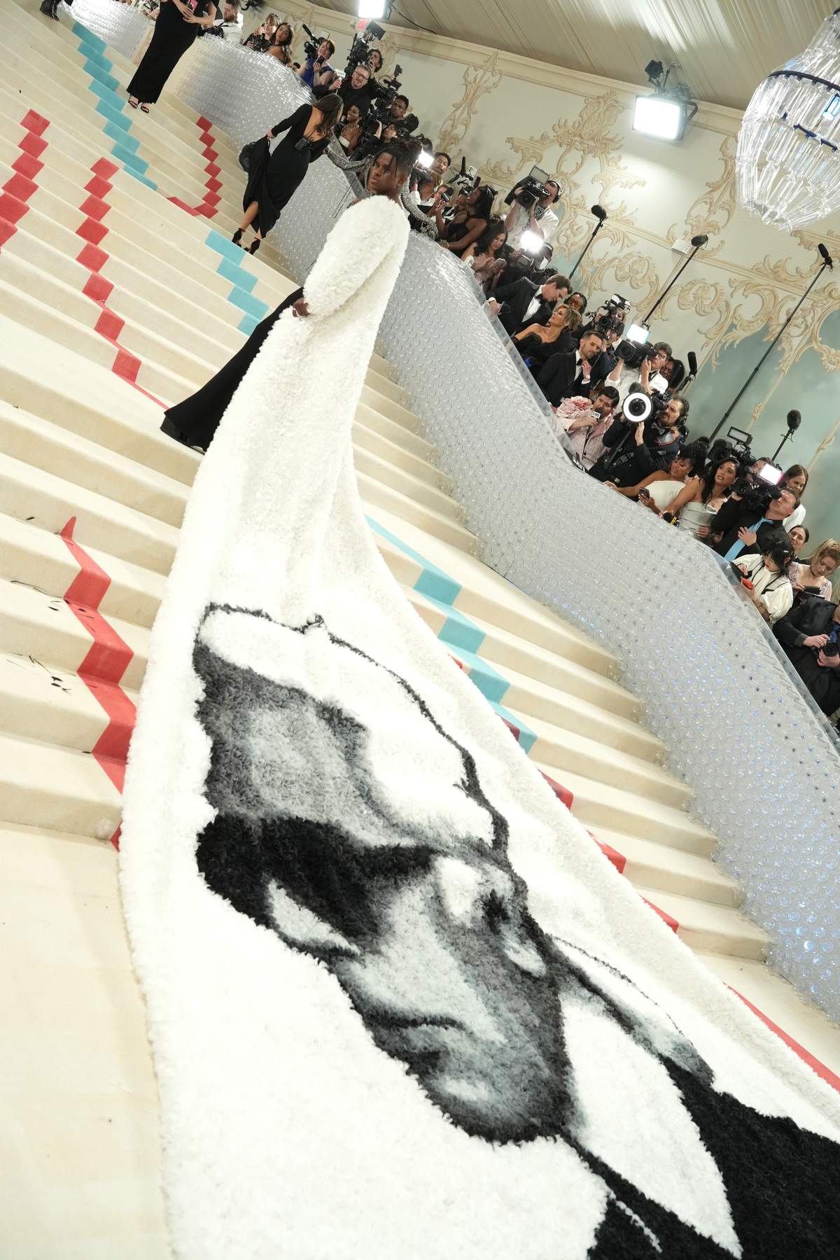 Jeremy Pope wearing a large white cape with a black portrait of Karl Lagerfeld printed on it.