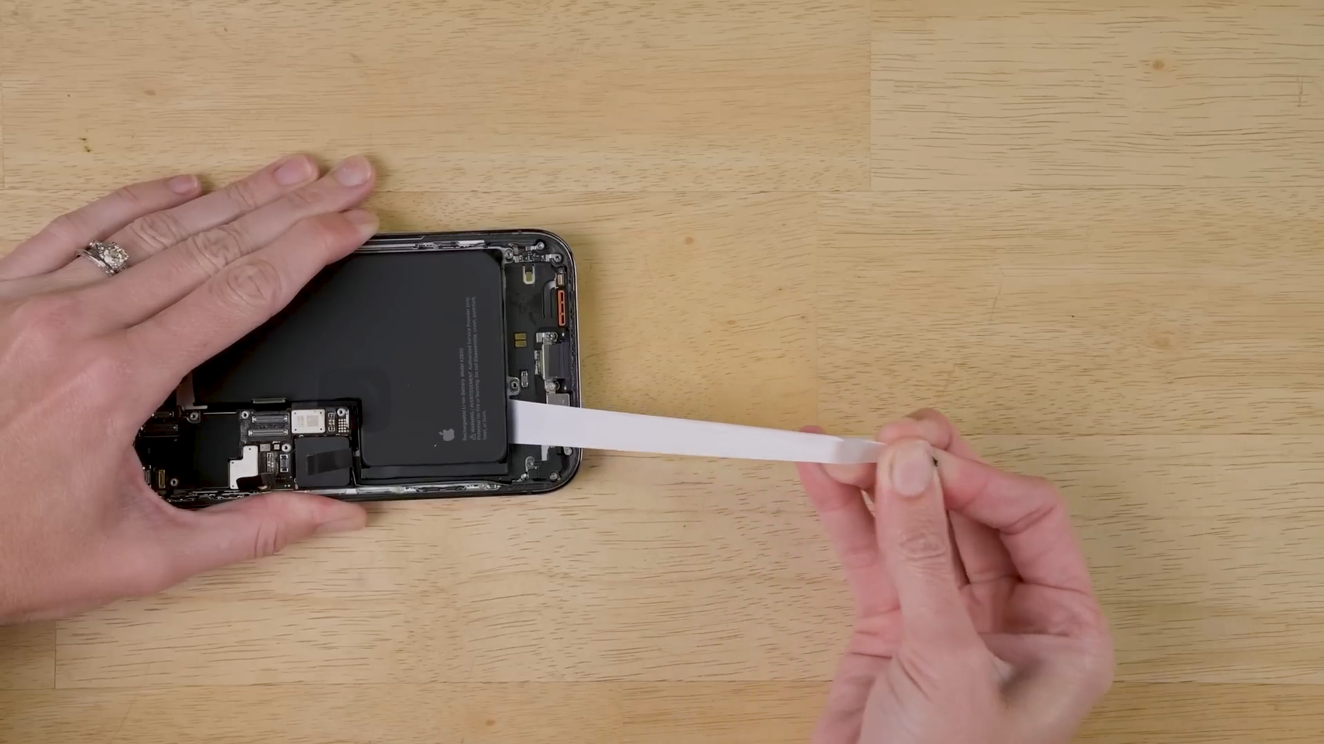 The adhesive securing an iPhone battery is place is removed in an iFixit teardown video on YouTube.