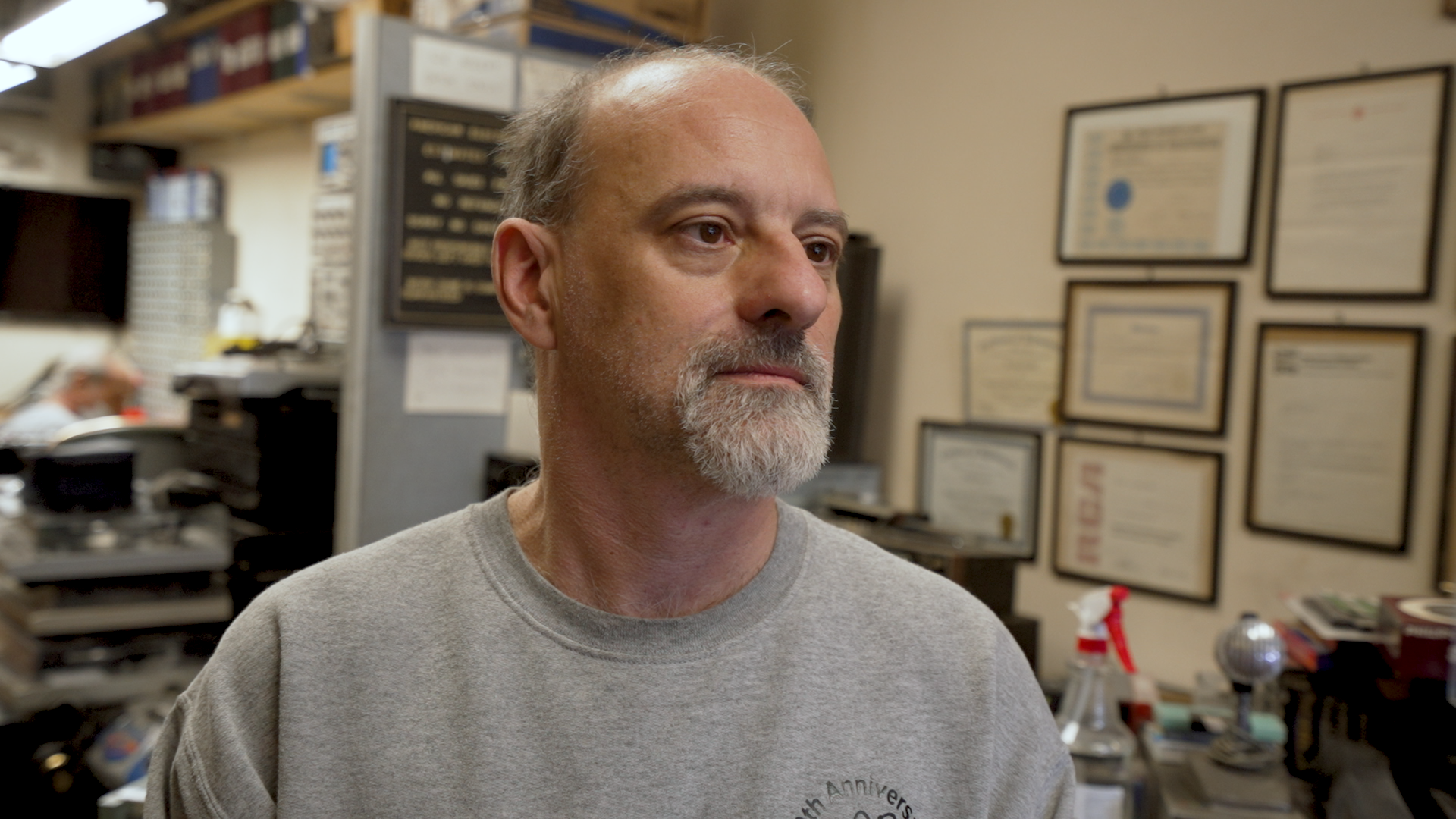 John Fadel at American Electronics. On the wall behind him is his electrical engineering degree and various other certificates.
