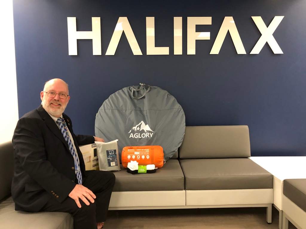 Max Chauvin is Halifax’s Housing and Homelessness Director. He sits next to a kit designed to help those sleeping rough, which includes a tent, sleeping bag, and socks.