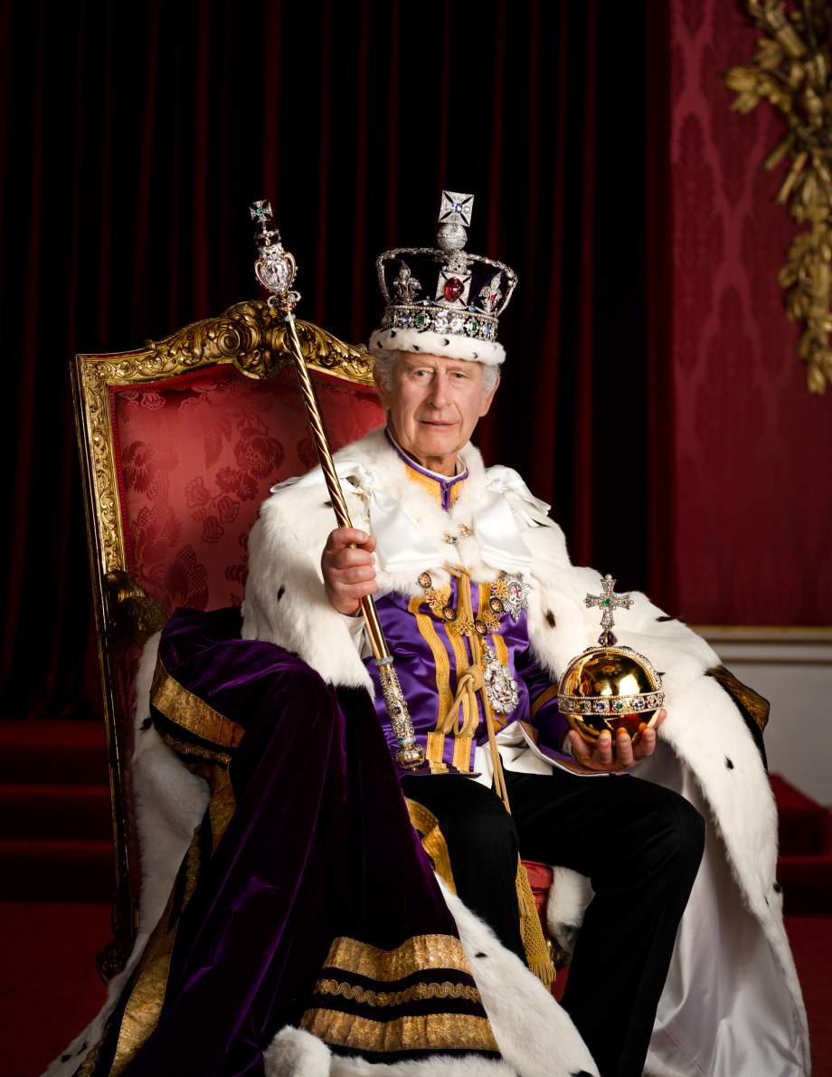 His Majesty is pictured in full regalia in the Throne Room at Buckingham Palace. His Majesty is wearing The Robe of Estate, The Imperial State Crown and is holding the Sovereign’s Orb and Sovereign’s Sceptre with Cross. His Majesty is seated on one of a pair of 1902 throne chairs that were made for the future King George V and Queen Mary for use at the Coronation of King Edward VII.