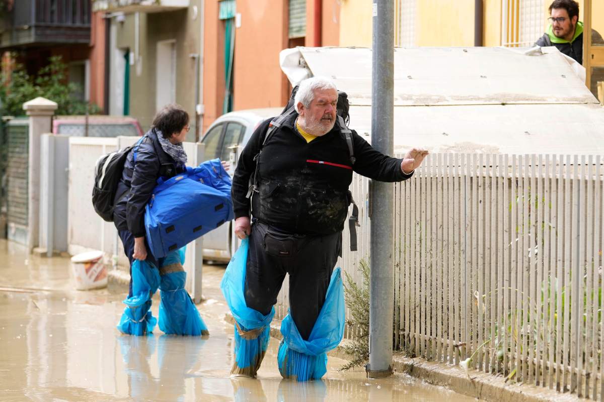 People walk in a flooded road in Faenza, Italy, Thursday, May 18, 2023. (AP Photo/Luca Bruno)