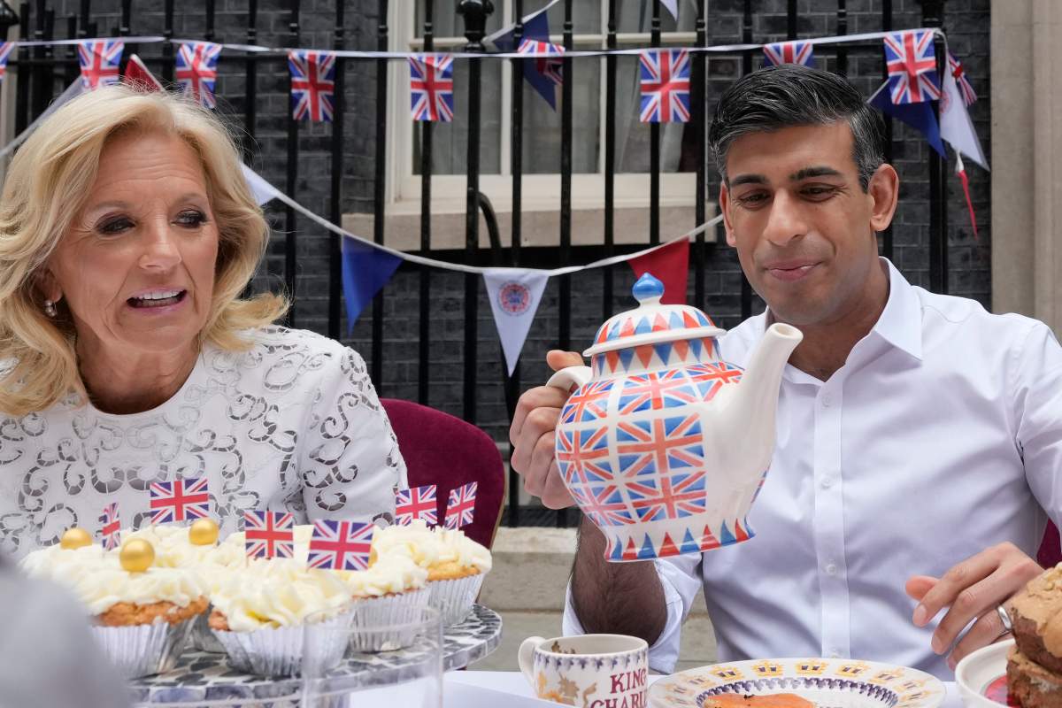 Prime Minister Rishi Sunak holds an oversize tea pot as he goes to pour a cup as he sits next to US First Lady Jill Biden as they attend the Big Lunch party at Downing Street in London Sunday, May 7, 2023. The Big Lunch is part of the weekend of celebrations for the Coronation of King Charles III. Guests at the big lunch include community heroes and Ukrainians displaced by the war, and youth groups. (AP Photo/Frank Augstein, Pool)