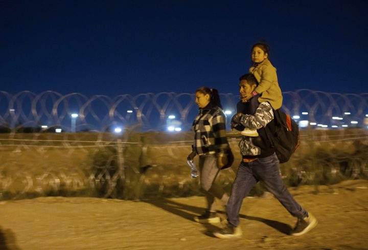 A migrant family from Peru walks towards a gate in the border fence after crossing from Ciudad Juarez, Mexico into El Paso, Texas, in the early hours of Thursday, May 11, 2023.