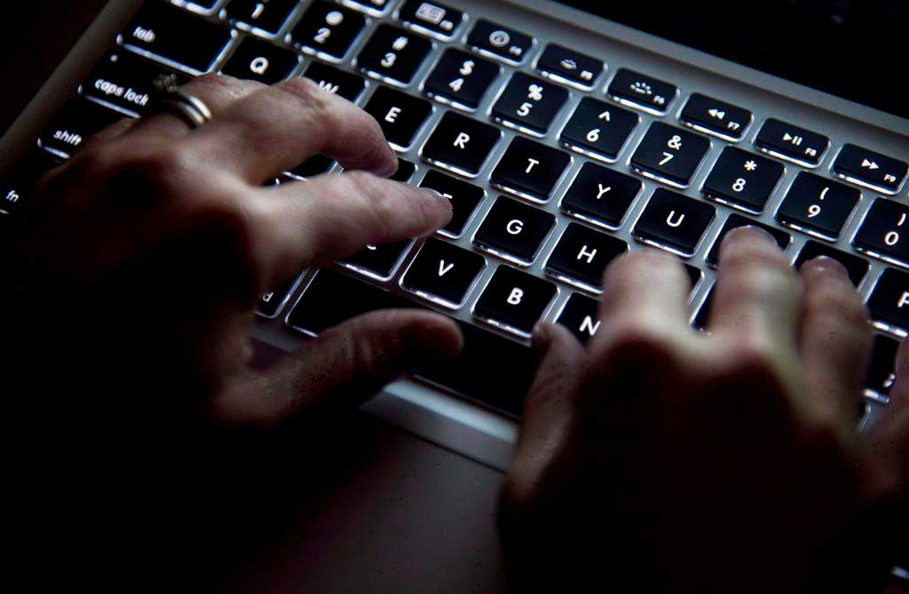 FILE. A woman uses her computer keyboard to type while surfing the internet in North Vancouver, B.C., on Dec. 19, 2012.  