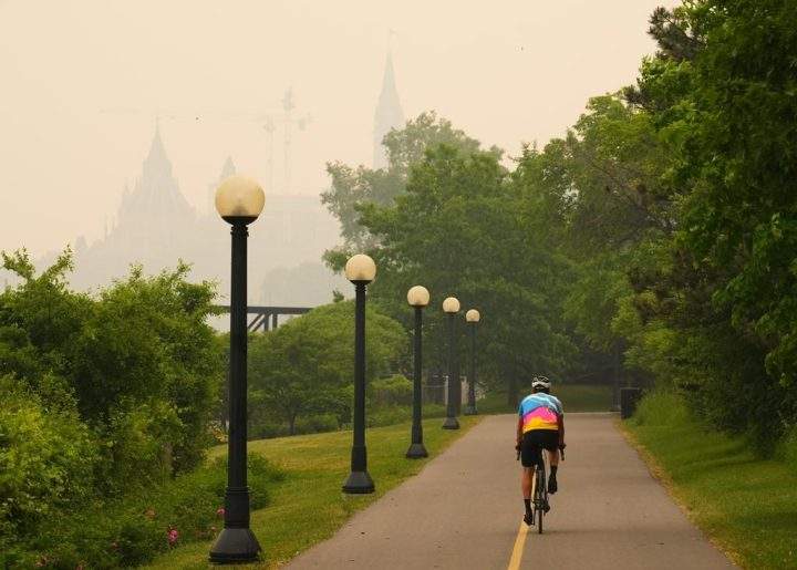 A cyclist rides as smoke from wildfires in Ontario and Quebec obscures Parliament Hill in Ottawa on Tuesday, June 6, 2023.
