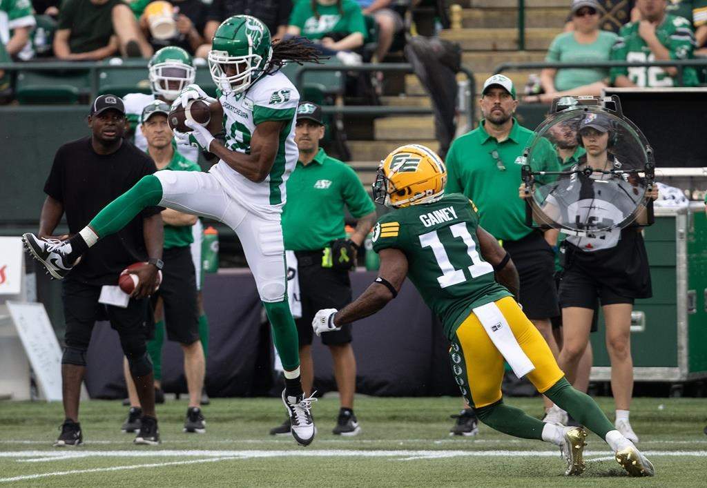 Saskatchewan Roughriders Derel Walker (18) makes the catch as Edmonton Elks Ed Gainey (11) tries to stop him during CFL action in Edmonton, Alta., on June 11, 2023. THE CANADIAN PRESS/Jason Franson.
