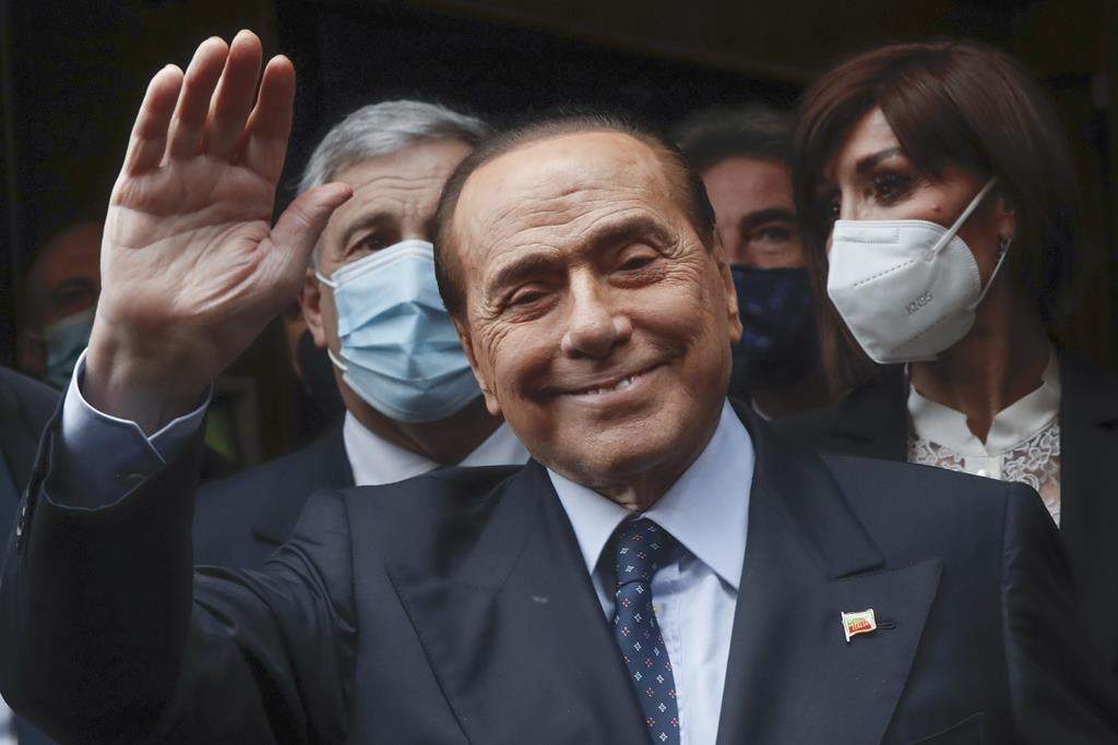 FILE – Former Italian Premier Silvio Berlusconi waves to reporters as he arrives at the Chamber of Deputies to meet Mario Draghi, in Rome, Feb. 9, 2021.