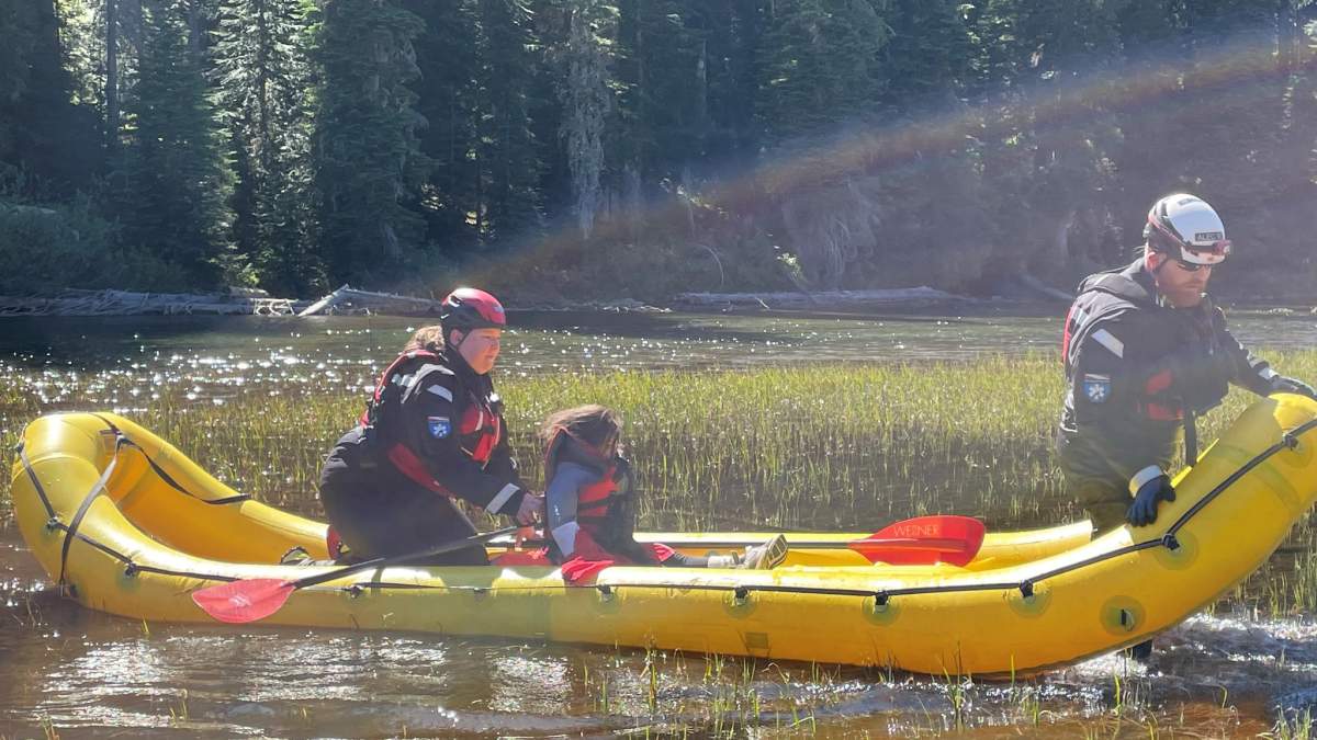 Shunghla Mashwani and two rescuers in an inflatable yellow boat on the river.