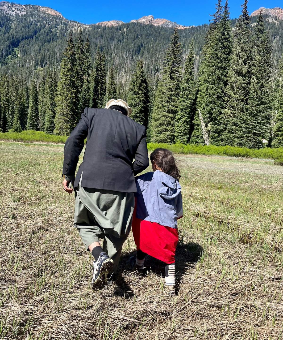 Shunghla Mashwani and a family member walk hand-in-hand. Their backs are to the camera.